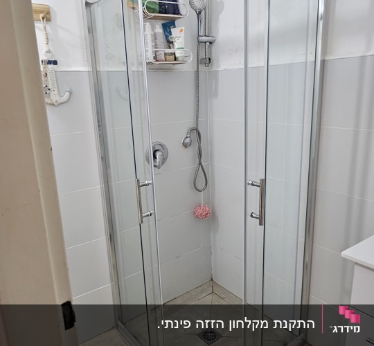 מקלחון זכוכית עם מדף מוצרים וראש מקלחת